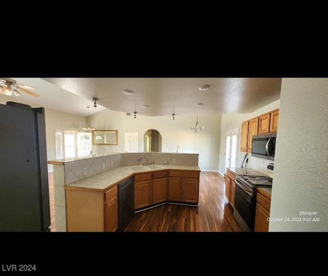 kitchen featuring kitchen peninsula, dark hardwood / wood-style flooring, sink, pendant lighting, and stainless steel appliances