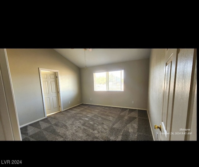 unfurnished room featuring lofted ceiling and dark colored carpet