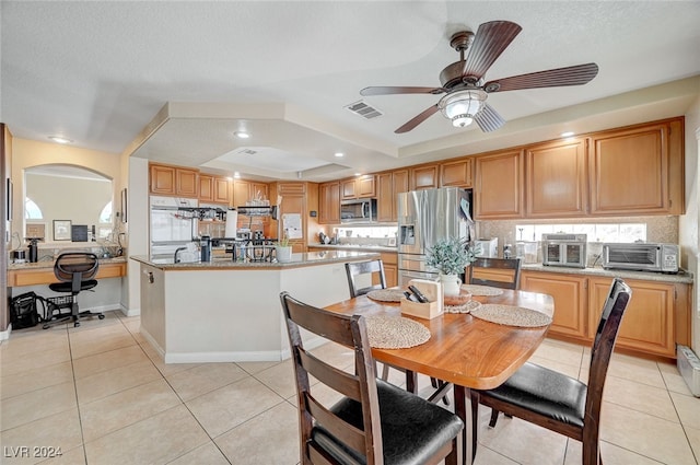 tiled dining room with a textured ceiling, a wealth of natural light, a tray ceiling, and ceiling fan