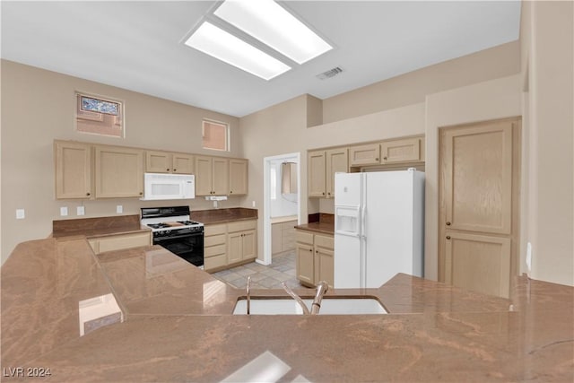 kitchen with kitchen peninsula, light brown cabinets, white appliances, and sink