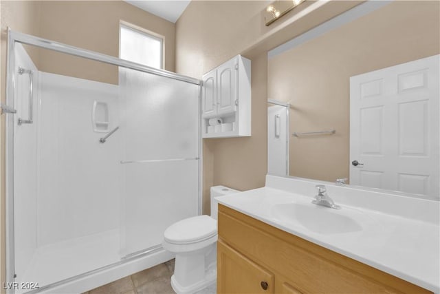 bathroom featuring tile patterned floors, vanity, toilet, and a shower with door