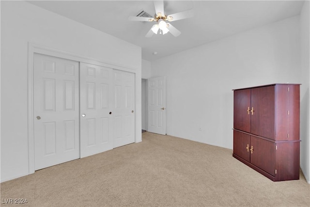 unfurnished bedroom with a closet, light colored carpet, and ceiling fan