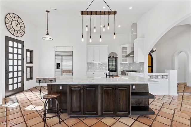 kitchen featuring dark brown cabinetry, stainless steel appliances, high vaulted ceiling, and a spacious island