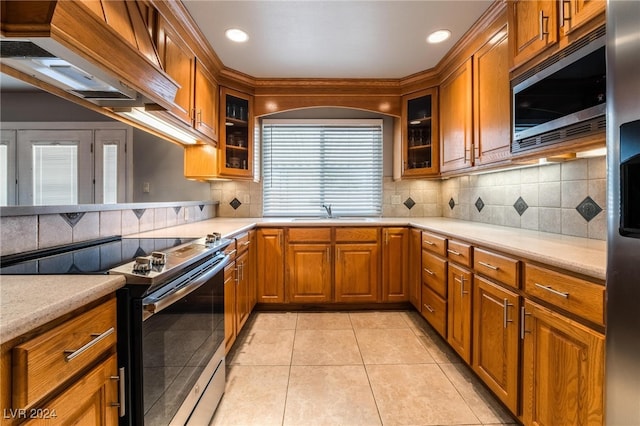 kitchen featuring premium range hood, sink, light tile patterned floors, tasteful backsplash, and stainless steel appliances