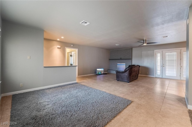 living room with ceiling fan, light tile patterned floors, and a brick fireplace