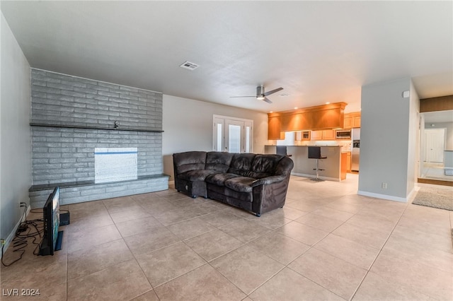 living room featuring light tile patterned floors, a brick fireplace, and ceiling fan