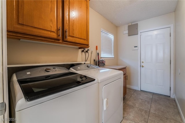 laundry area featuring light tile patterned flooring, cabinets, a textured ceiling, and independent washer and dryer