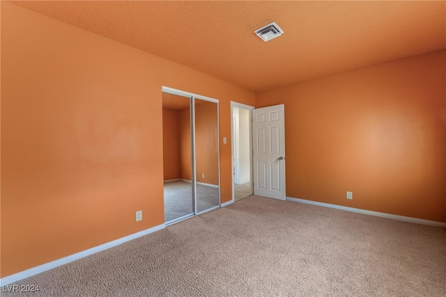 unfurnished bedroom featuring carpet, a textured ceiling, and a closet