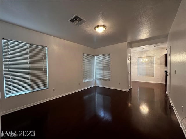 spare room featuring a chandelier and dark hardwood / wood-style flooring