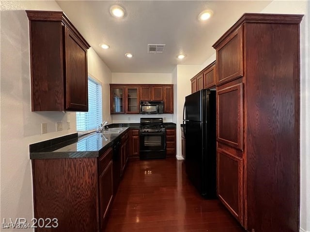 kitchen with dark wood-type flooring, black appliances, and sink