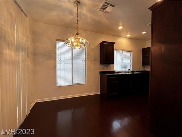 kitchen featuring dark brown cabinetry, a chandelier, decorative light fixtures, and dark hardwood / wood-style floors