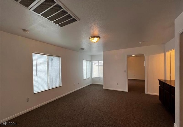 empty room with a textured ceiling and dark carpet