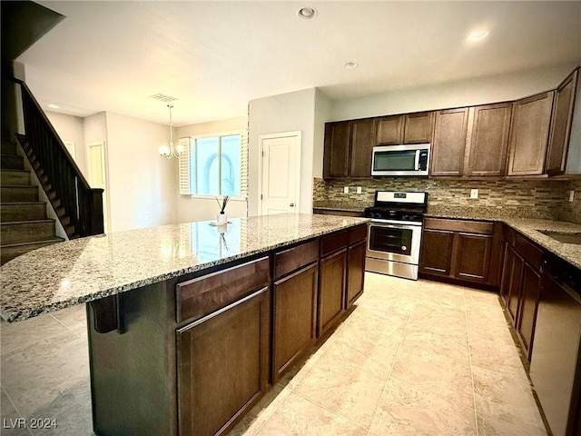 kitchen with a center island, stainless steel appliances, an inviting chandelier, pendant lighting, and dark brown cabinets