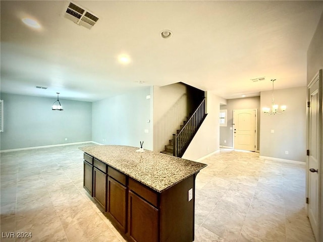 kitchen featuring a center island, an inviting chandelier, light stone counters, pendant lighting, and dark brown cabinets