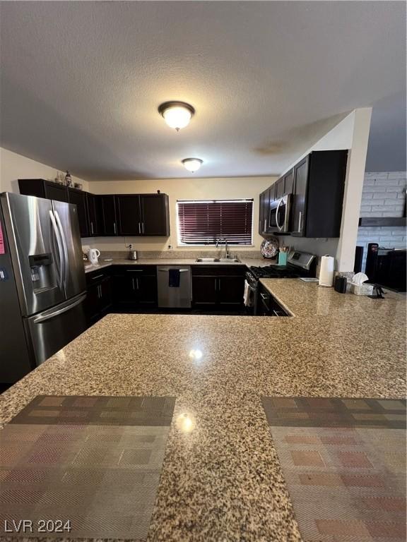 4369 Greenhill Dr, Las Vegas, NV 89121 - kitchen with appliances with stainless steel finishes, a sink, dark cabinetry, and light stone counters