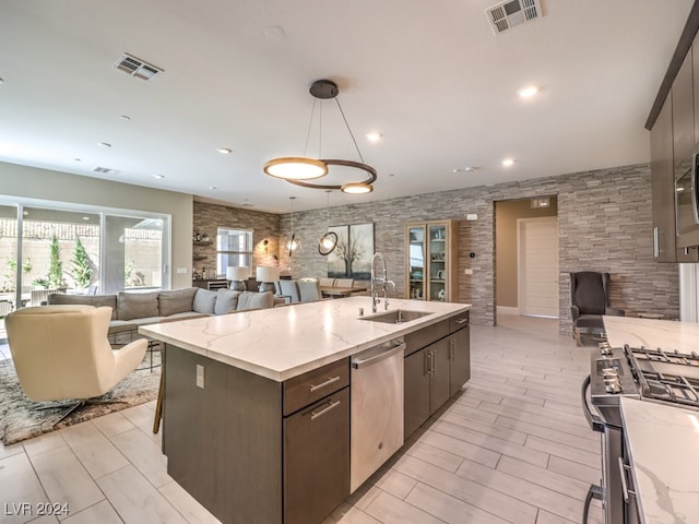 kitchen with decorative light fixtures, sink, a center island with sink, appliances with stainless steel finishes, and dark brown cabinetry