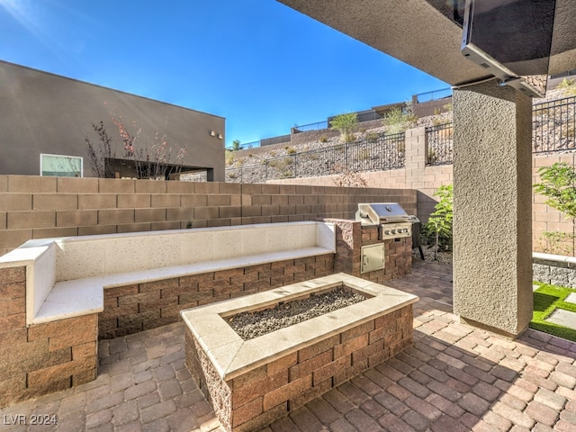 view of patio with an outdoor kitchen, a fire pit, and a grill