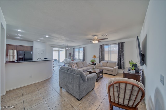 tiled living room with ceiling fan with notable chandelier