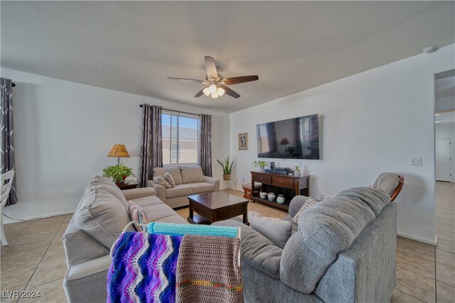 living room with ceiling fan, a textured ceiling, and light tile patterned flooring