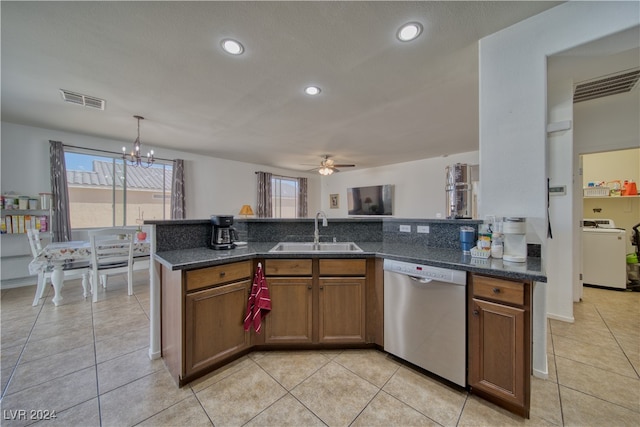 kitchen with washer / clothes dryer, hanging light fixtures, dark stone counters, sink, and stainless steel dishwasher