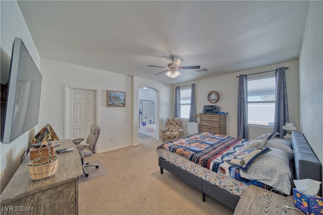 bedroom featuring connected bathroom, ceiling fan, a textured ceiling, and light colored carpet