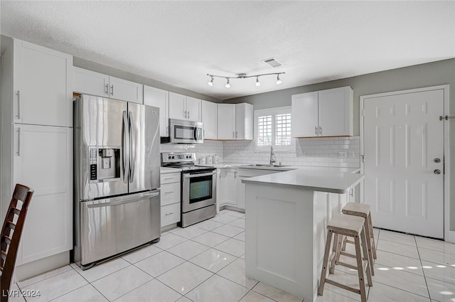 kitchen featuring white cabinetry, appliances with stainless steel finishes, sink, and a kitchen bar