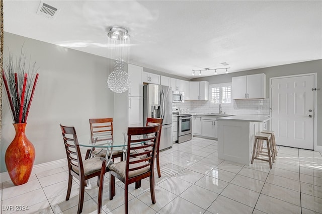 kitchen featuring sink, appliances with stainless steel finishes, a kitchen bar, and white cabinetry