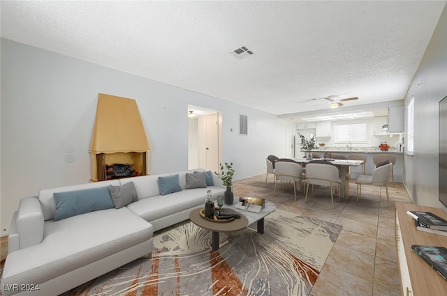 living room featuring ceiling fan, light tile patterned flooring, and a textured ceiling