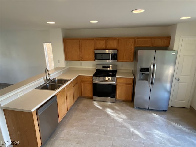 kitchen with sink, appliances with stainless steel finishes, kitchen peninsula, and light tile patterned flooring