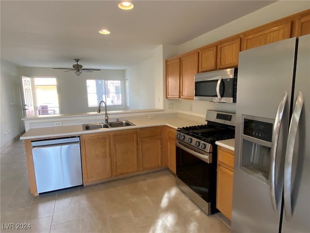 kitchen with appliances with stainless steel finishes, kitchen peninsula, sink, and ceiling fan