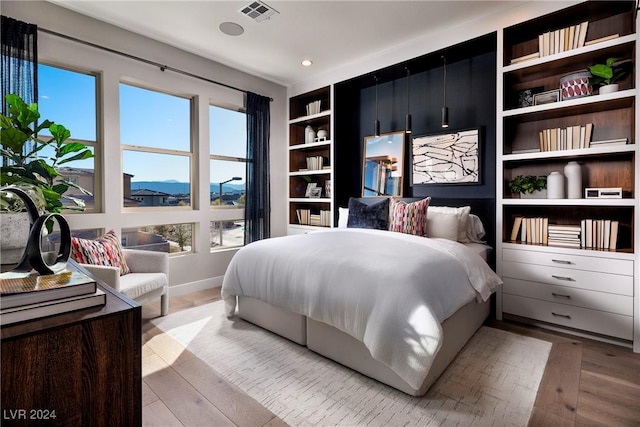 bedroom with a mountain view and light hardwood / wood-style flooring