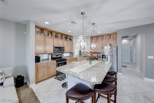 kitchen featuring light stone countertops, a center island, hanging light fixtures, a breakfast bar area, and appliances with stainless steel finishes