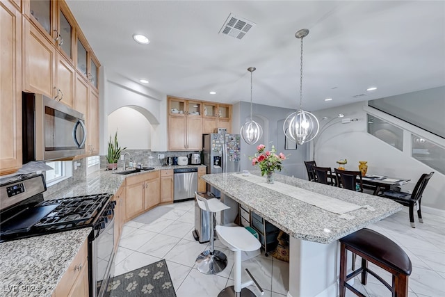 kitchen featuring backsplash, light stone counters, stainless steel appliances, and a breakfast bar area