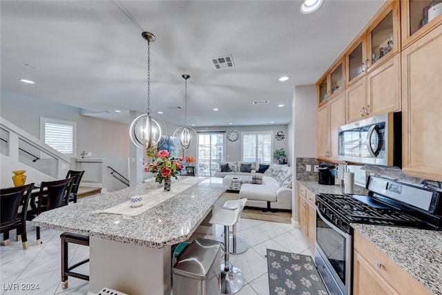 kitchen featuring light stone countertops, appliances with stainless steel finishes, a kitchen island, and a breakfast bar area