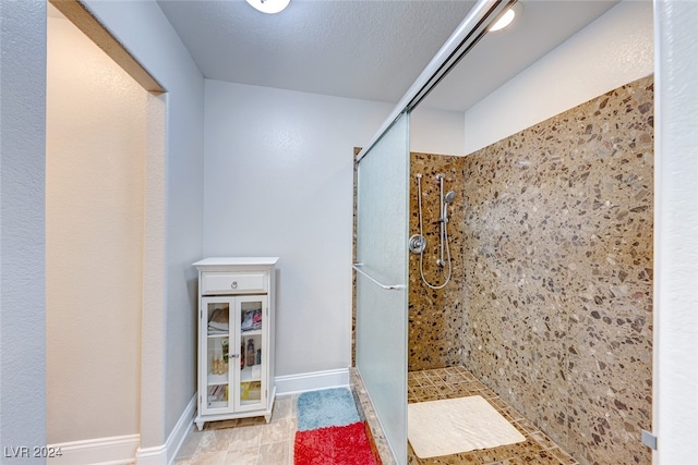 bathroom with a tile shower and a textured ceiling