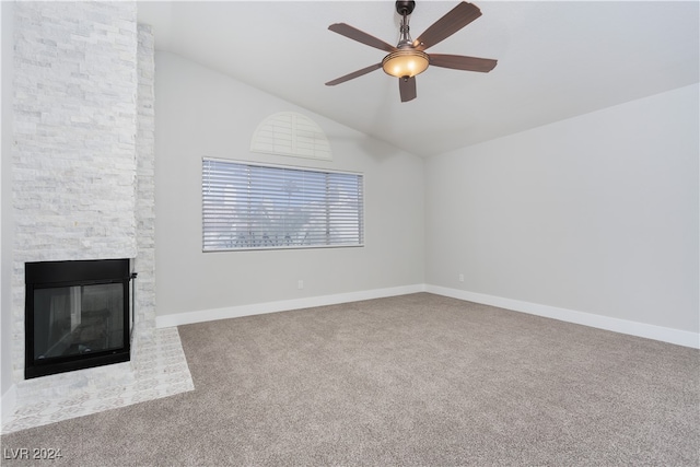 unfurnished living room with vaulted ceiling, ceiling fan, a large fireplace, and carpet floors