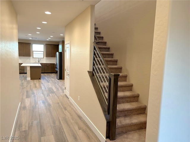 stairway with hardwood / wood-style floors and sink