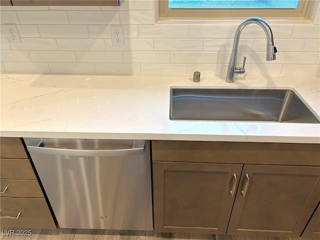 kitchen with light stone counters, dishwasher, and sink