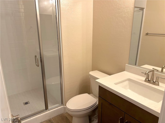 bathroom featuring hardwood / wood-style floors, vanity, a shower with shower door, and toilet