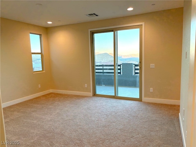 carpeted spare room featuring a mountain view and a healthy amount of sunlight