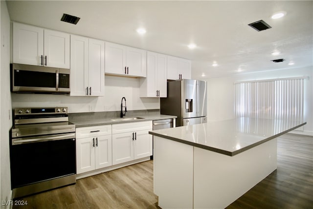 kitchen featuring appliances with stainless steel finishes, light hardwood / wood-style flooring, white cabinets, and sink