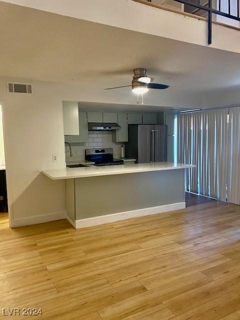 kitchen featuring kitchen peninsula, stainless steel appliances, light wood-type flooring, and ceiling fan