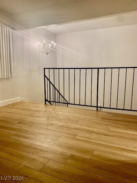 unfurnished room featuring a chandelier and light wood-type flooring