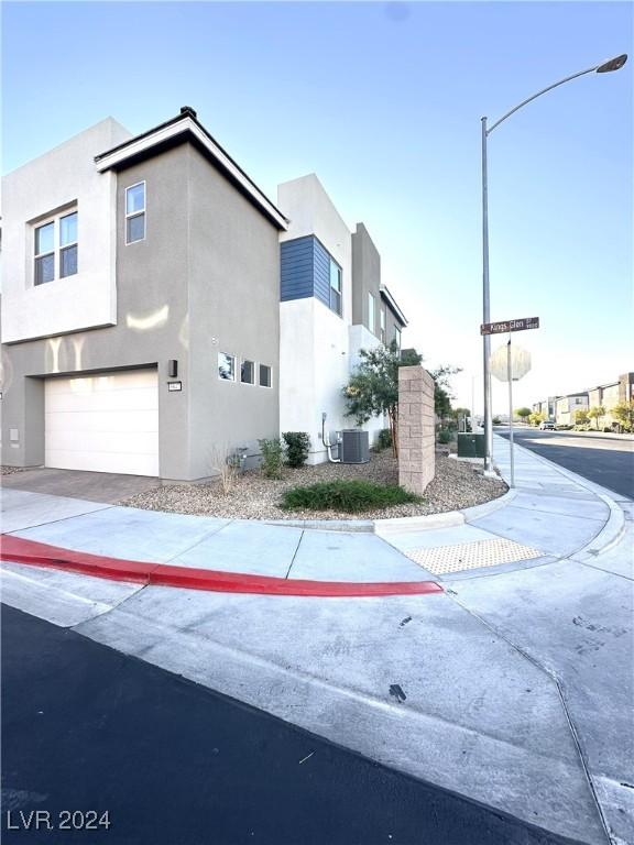 9847 Kings Glen St, Las Vegas, NV 89141 - view of side of property featuring stucco siding, an attached garage, driveway, and central air condition unit