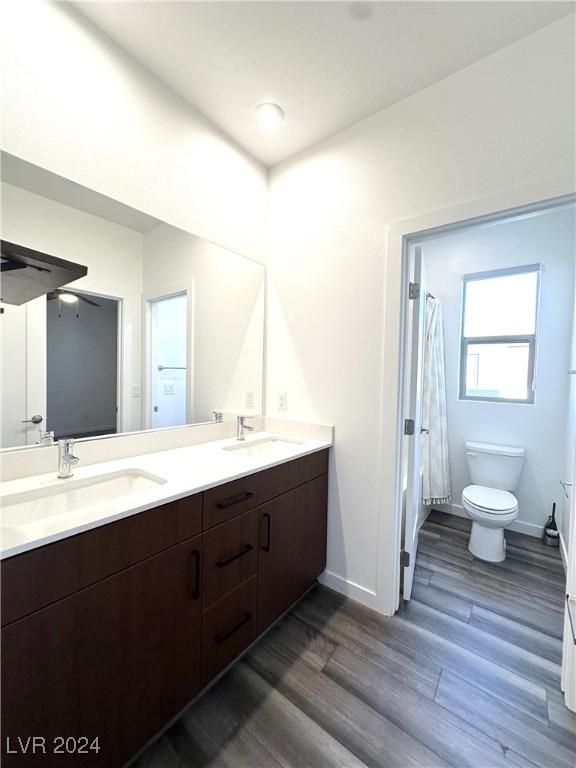 9847 Kings Glen St, Las Vegas, NV 89141 - full bath with wood finished floors, toilet, double vanity, and baseboards