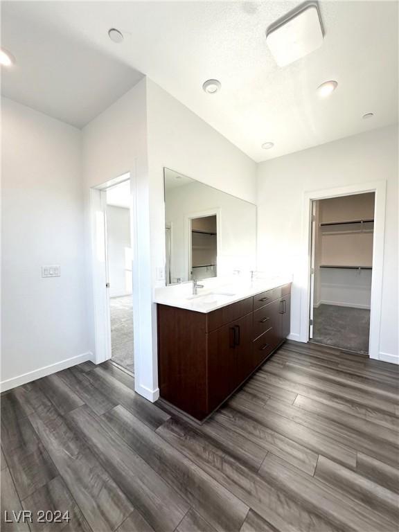 9847 Kings Glen St, Las Vegas, NV 89141 - full bath with wood finished floors, double vanity, a walk in closet, and baseboards