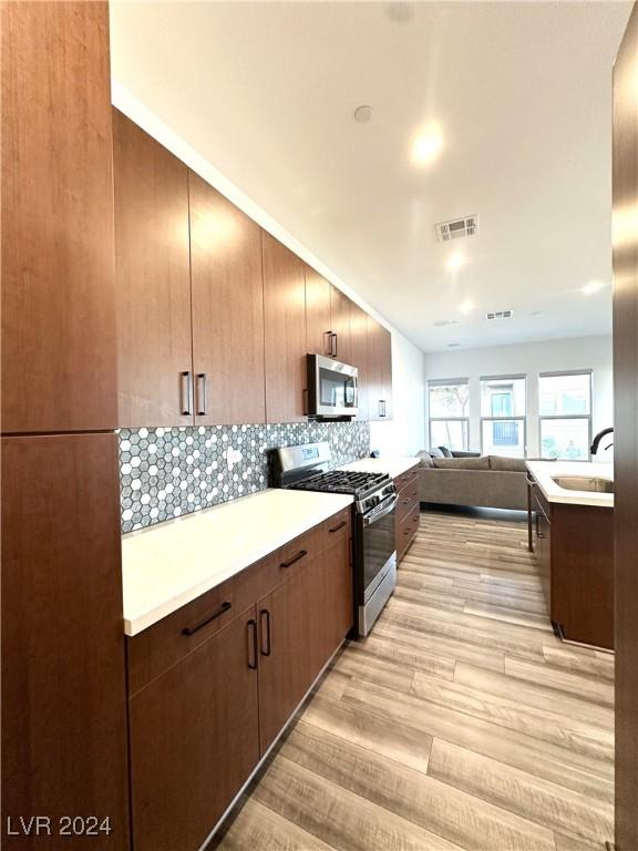 9847 Kings Glen St, Las Vegas, NV 89141 - kitchen featuring stainless steel appliances, light wood-type flooring, light countertops, open floor plan, and a sink