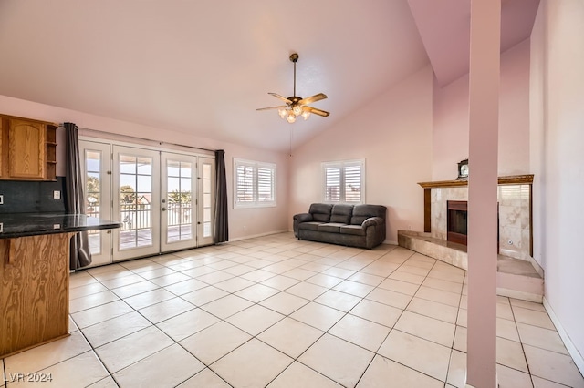 tiled living room with a fireplace, french doors, high vaulted ceiling, and ceiling fan