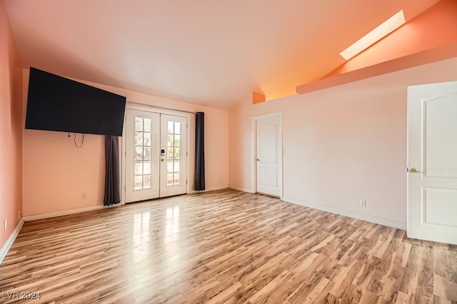 spare room with french doors, light wood-type flooring, and lofted ceiling with skylight