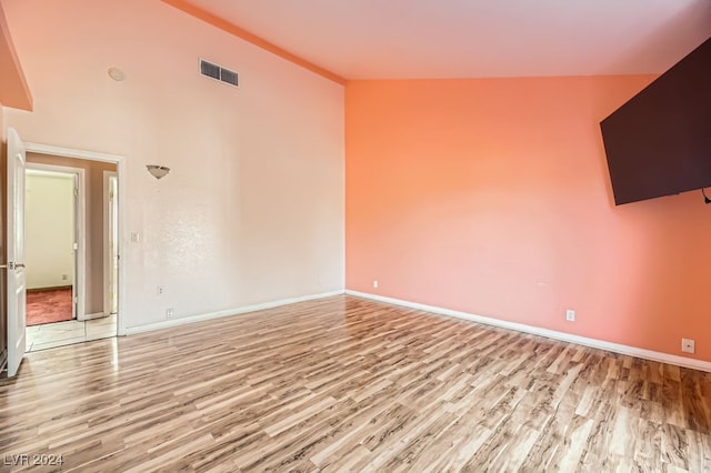 unfurnished room featuring light hardwood / wood-style floors and lofted ceiling